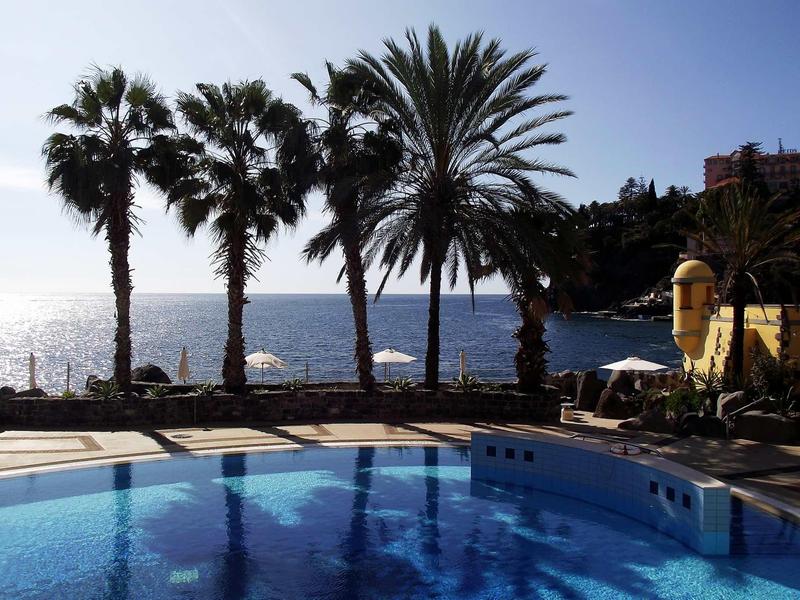 Piscine avec palmiers au bord de la mer au coucher du soleil, ambiance de vacances paisible