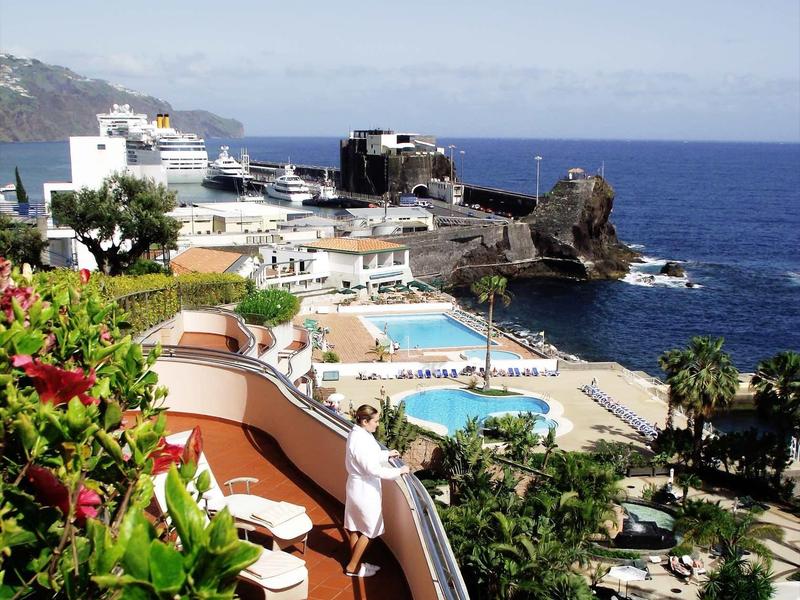 Vue sur hôtel avec piscines, terrasse et mer près de la côte sous un ciel clair