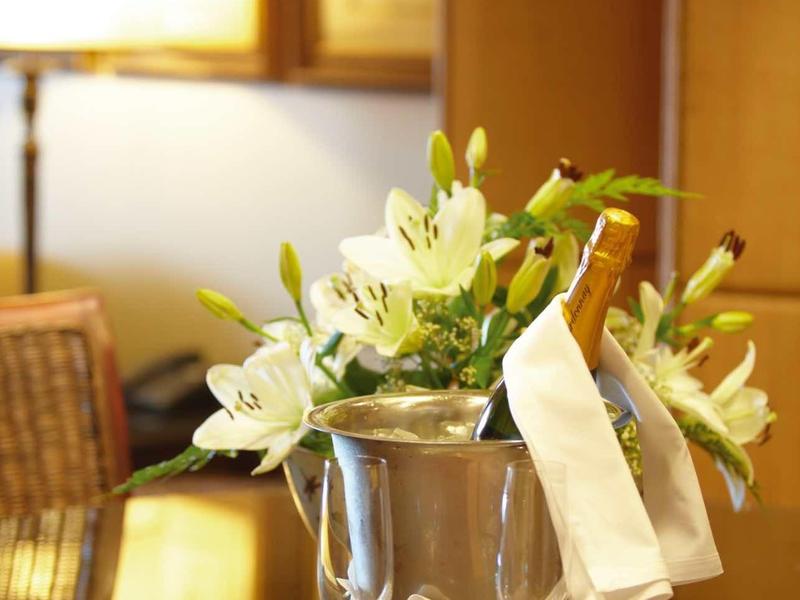 Bouteille de champagne dans un seau à glace avec des verres et des lys blancs sur une table.
