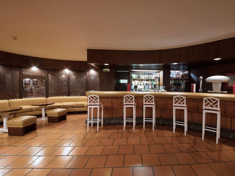 Moderní hotelový bar s barovými židličkami, útulným posezením a tlumeným osvětlením.