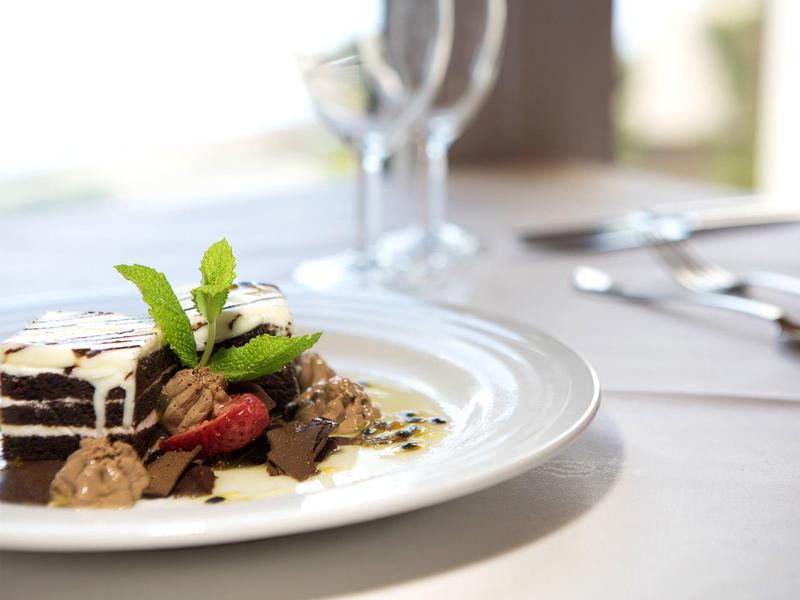 Elegantní dezert s čokoládovým dortem, vanilkovou zmrzlinou, bobulemi a mátou podávaný na bílém talíři