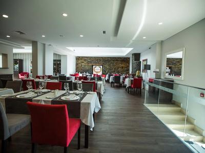 Modern eingerichtetes Restaurant mit roten Stühlen und elegant gedeckten Tischen.