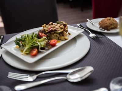 Ein Teller mit Salat und belegtem Sandwich auf einem gedeckten Tisch in einem Restaurant.