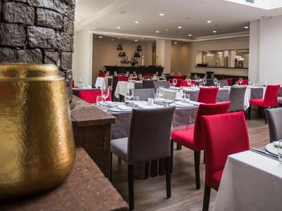 Elegantes Restaurant mit rot und grau bezogenen Stühlen und gedeckten Tischen in einem Hotel.