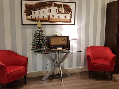 Zwei rote Sessel vor einer gestreiften Wand mit Mini-Weihnachtsbaum und Vintage-Radio auf einem Glastisch.