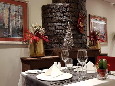 Festlich dekorierter Tisch in einem Restaurant mit Kamin und Kunst an den Wänden.