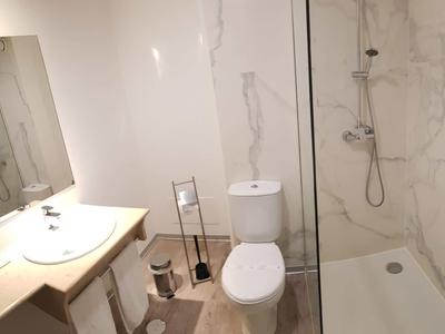 Modernes Badezimmer mit Toilette, Waschbecken und begehbarer Dusche mit Glaswand.