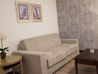 Wohnzimmer mit beigem Sofa, braunem Couchtisch, Sideboards und dekorativer Wand.