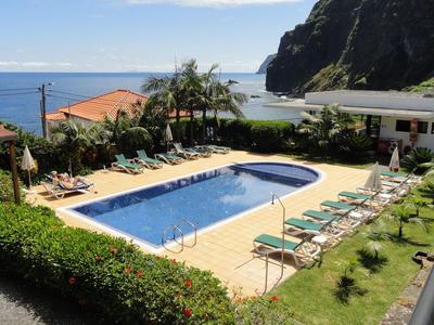 Hotel pool with sun loungers and view of the sea and a cliff
