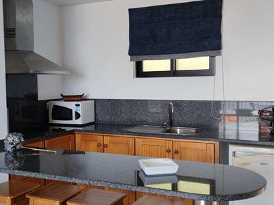 Modern hotel kitchen with wooden cabinets, black countertop, and built-in appliances.