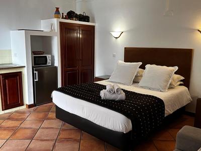 Cozy hotel room with double bed, nightstands, and kitchenette with microwave.