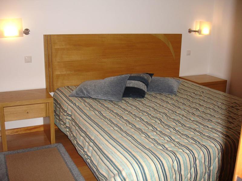 Cozy hotel room with double bed, wooden frame, nightstands, softly lit.