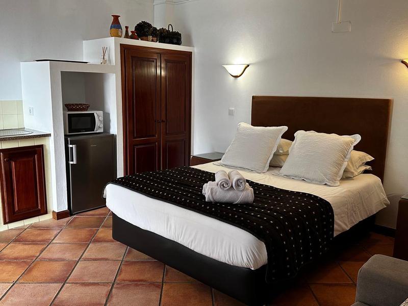 Cozy hotel room with double bed, nightstands, and kitchenette with microwave.