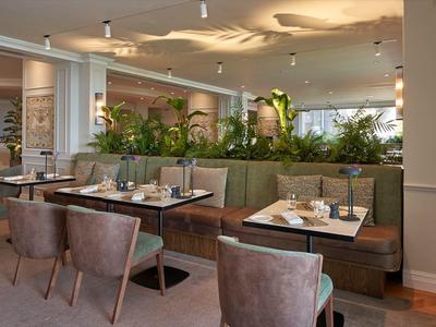 Ristorante elegante con sedute moderne e piante verdi come divisori.