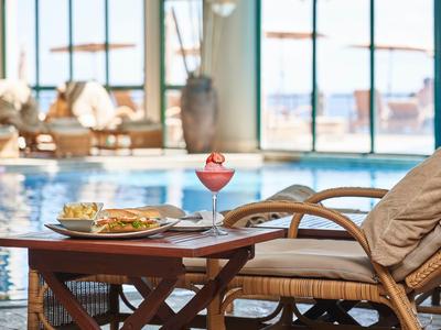 Area piscina rilassante con tavolo, bevanda e snack in uno spazio luminoso e arioso.