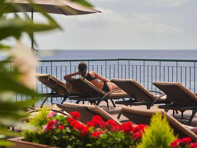 Persona che si rilassa su una sdraio con vista mare e balcone in vacanza.