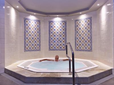 Persona che si rilassa in una vasca idromassaggio riscaldata con piastrelle decorative.