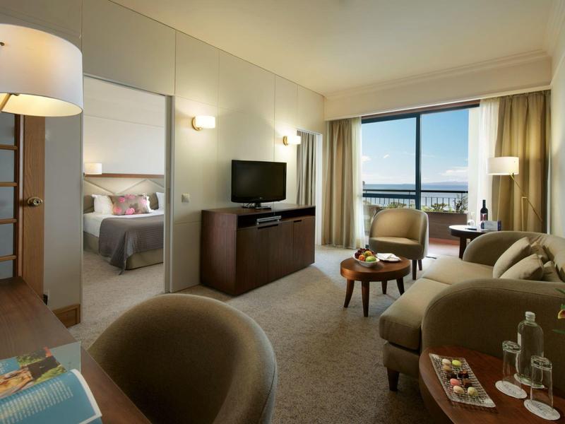 Camera d'hotel moderna con area salotto e vista su una terrazza e acqua