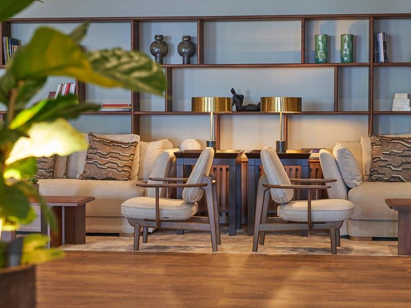 Accogliente zona lounge con poltrone, divani e cuscini decorativi davanti a una mensola aperta.