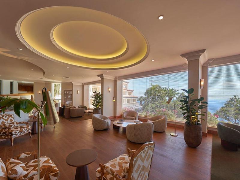 Area lounge luminosa dell'hotel con comode poltrone e grandi finestre con vista sul mare.