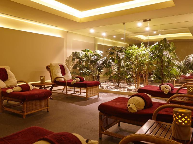 Sala relax con lettini e piante verdi in un ambiente illuminato caldamente