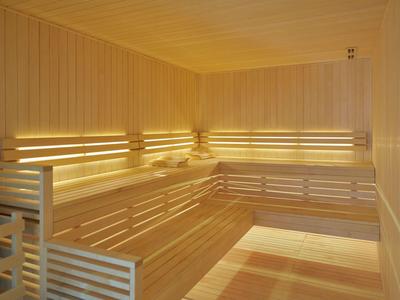 Světla, moderní sauna s dřevěnými lavicemi a teplým osvětlením.
