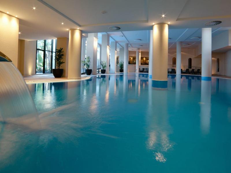 Vnitřní bazén s vodopádovou sprchou a relaxačním osvětlením v hotelu