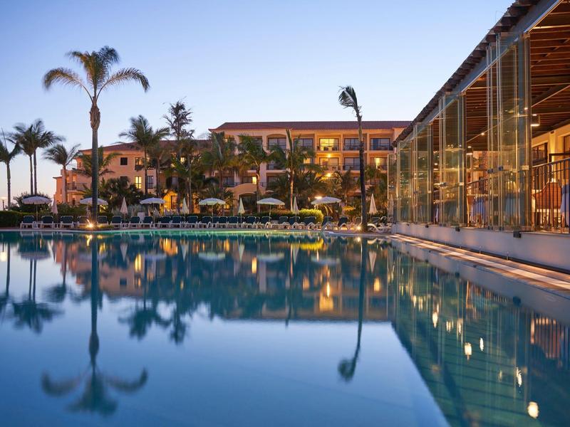 Luxusní hotel s osvětleným bazénem a palmami za soumraku