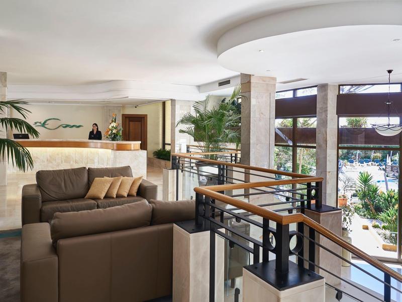 Moderní hotelová lobby s pohodlnými pohovkami a velkou skleněnou stěnou s výhledem na venkovní prostor