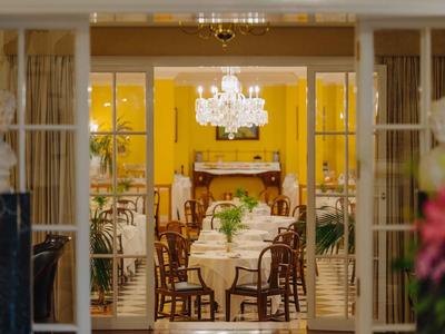 Elegantes Esszimmer mit gedecktem Tisch, Holzstühlen, Kronleuchter und gelben Wänden.