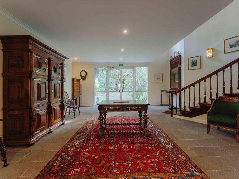 Großes Wohnzimmer mit rotem Teppich, dunkelbraunem Holzschrank, Tisch und Treppe an der Wand.