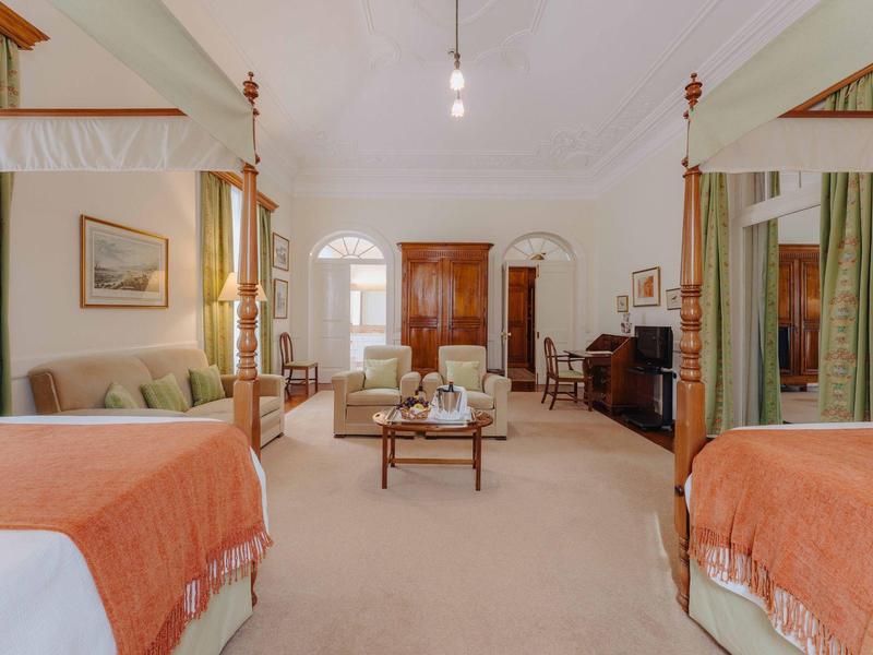 Geräumiges Schlafzimmer mit Doppelbett, Holzmöbeln, Teppichboden und weichen Vorhängen.