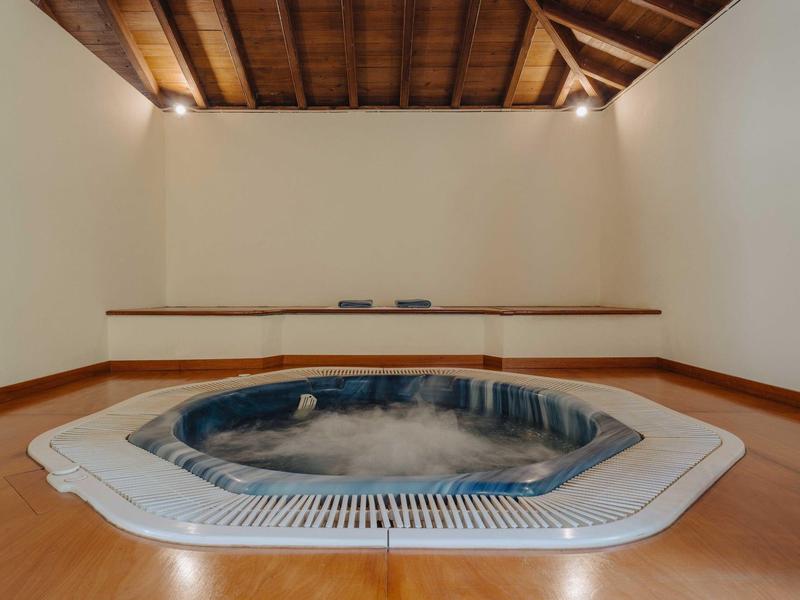 Innenraum mit eingebautem Whirlpool, Holzdecke, Holzfußboden und weißen Wänden.