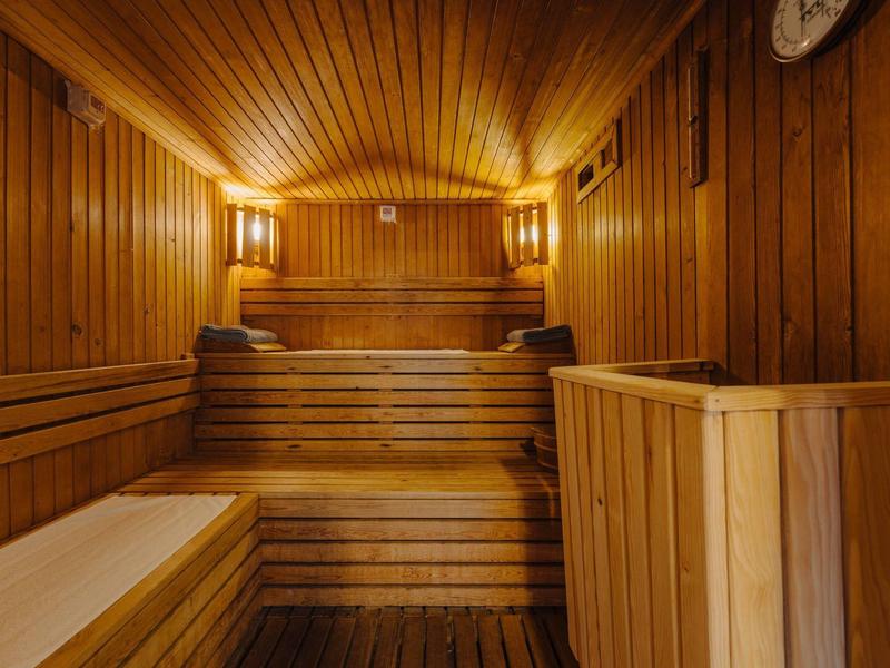 Holzsauna mit mehrstufigen Sitzbänken, wandhoher Holzverkleidung und warmem Licht.