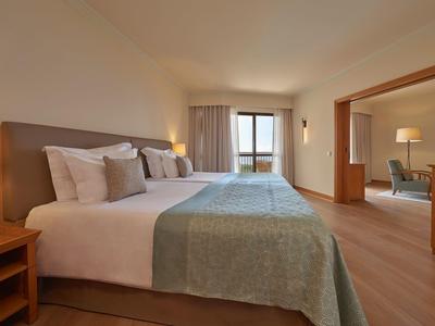 Habitación de hotel luminosa con camas grandes y vista al mar a través de la ventana.