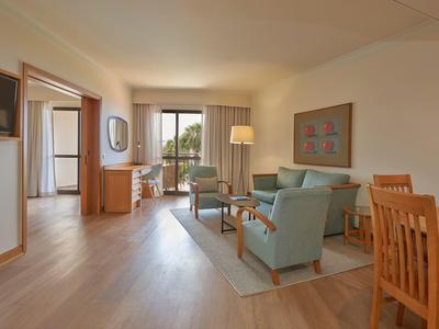 Sala luminosa con suelo de madera, zona de estar, comedor y acceso a balcón o terraza.