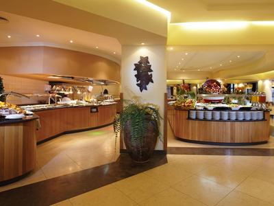 Área de buffet de desayuno con diseño moderno, iluminación cálida y mostradores de madera en un hotel.