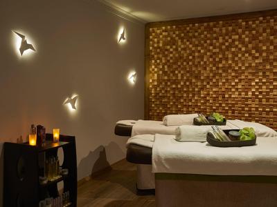 Gemütlicher Wellnessraum mit zwei Liegen, warmem Licht und dekorativen Wandlampen.