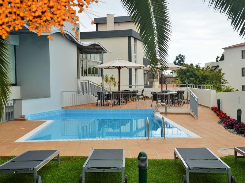 Nowoczesny basen na zewnątrz z leżakami i miejscem do siedzenia w hotelu z palmami.