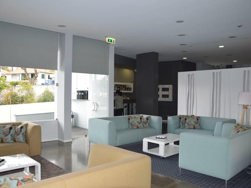 Nowoczesna lobby hotelowa z sofami, stolikami kawowymi i dużymi oknami wpuszczającymi dużo światła.