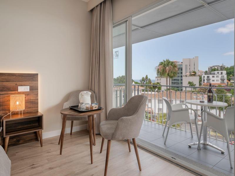 Nowoczesny pokój hotelowy z balkonem, miejscem do siedzenia i widokiem na miasto.