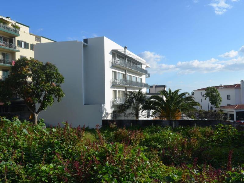 Budynek hotelu z balkonami otoczony roślinnością pod niebieskim niebem