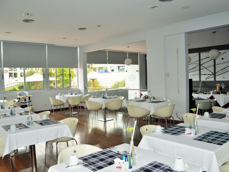 Nowoczesna restauracja z białymi obrusami i dużymi oknami z widokiem na patio.