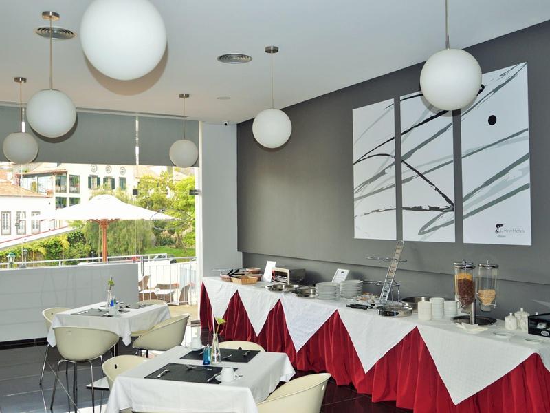 Nowoczesna sala śniadaniowa z nakrytymi stołami i dużymi oknami z widokiem na miasto.