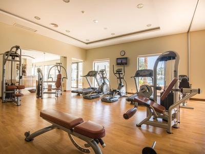 Salle de sport lumineuse avec divers équipements d'exercice et sol en bois.