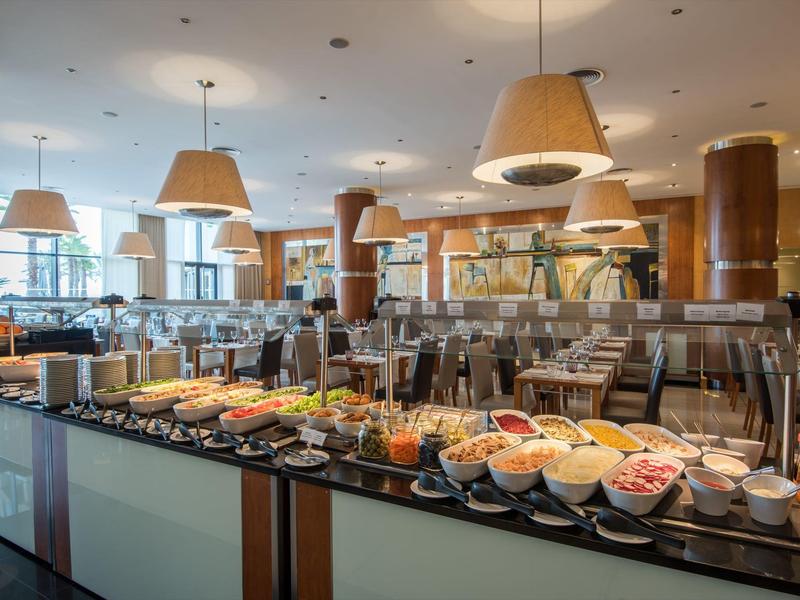 Bufet z różnorodnym jedzeniem w jasnej jadalni z nowoczesnym wystrojem.