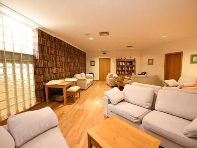 Salon lumineux avec canapés confortables, sol en bois et grande façade vitrée.