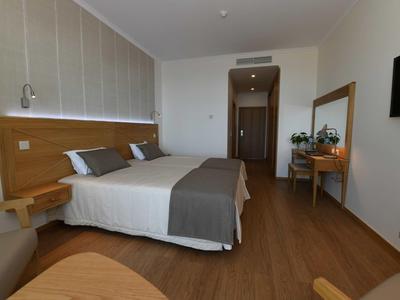 Chambre d'hôtel moderne avec lit double, sol en bois et bureau avec miroir.