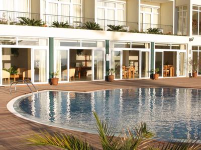 Une piscine d'hôtel ronde avec eau bleue claire et terrasse ensoleillée.