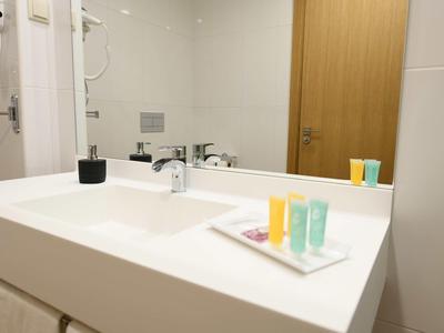 Évier de salle de bain blanc avec distributeurs de savon et articles de toilette sur le comptoir.